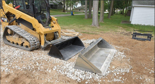 Vestil skid steer bucket attachment for heavy machinery, showing a durable metal bucket with mounting brackets.