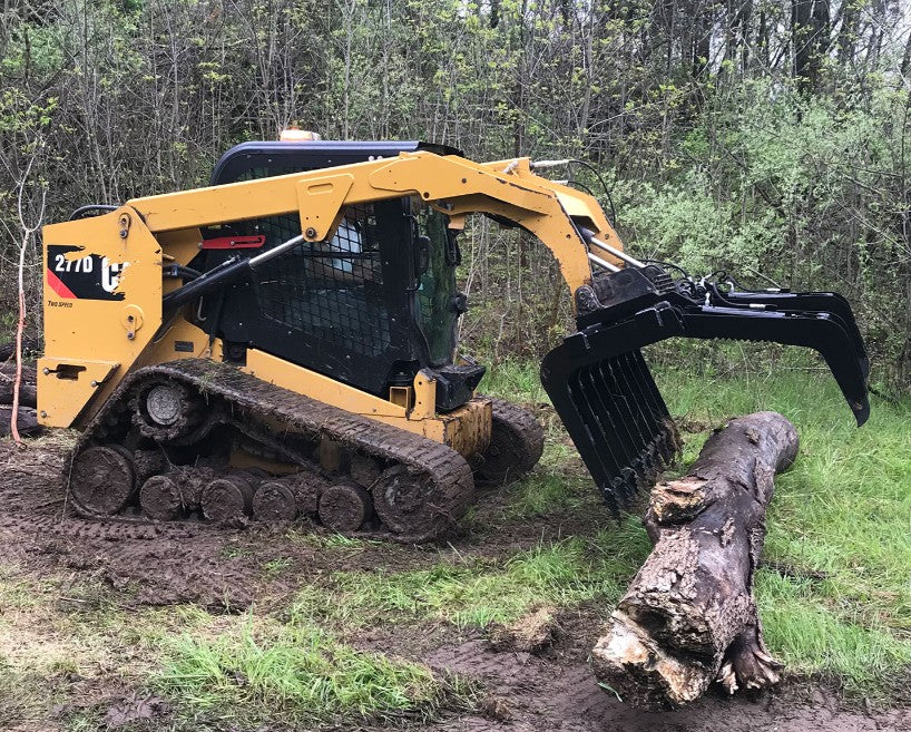 Vestil skid steer grab bucket attachment connected to heavy machinery for lifting and transporting materials.